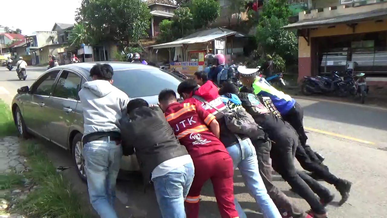 Pulang Piket, Seorang Polisi Lalu Lintas Sempatkan Dorong Mobil Pemudik yang Mogok