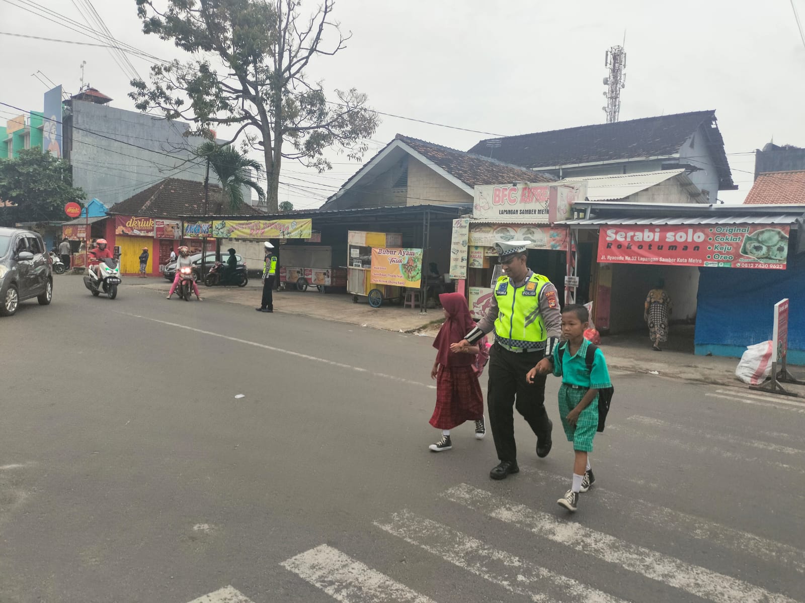 Wujud Kepedulian, Anggota Sat Lantas Polres Metro Bantu Anak Sekolah Menyebrangkan Jalan